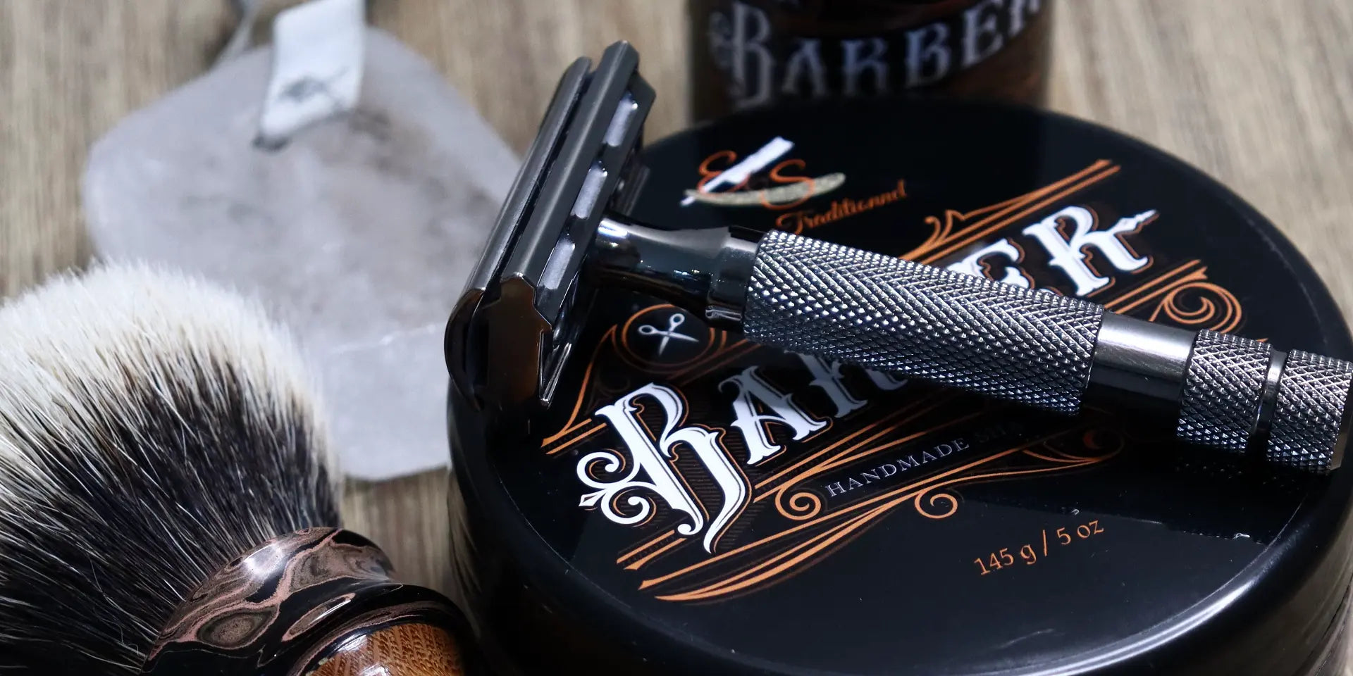 Un rasoir posé sur un savon de rasage BARBER et un blaireau de rasage et un après-rasage posés à côté.